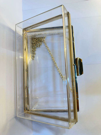 Acrylic clutch bag with gold frame, gold chain strap, and open front