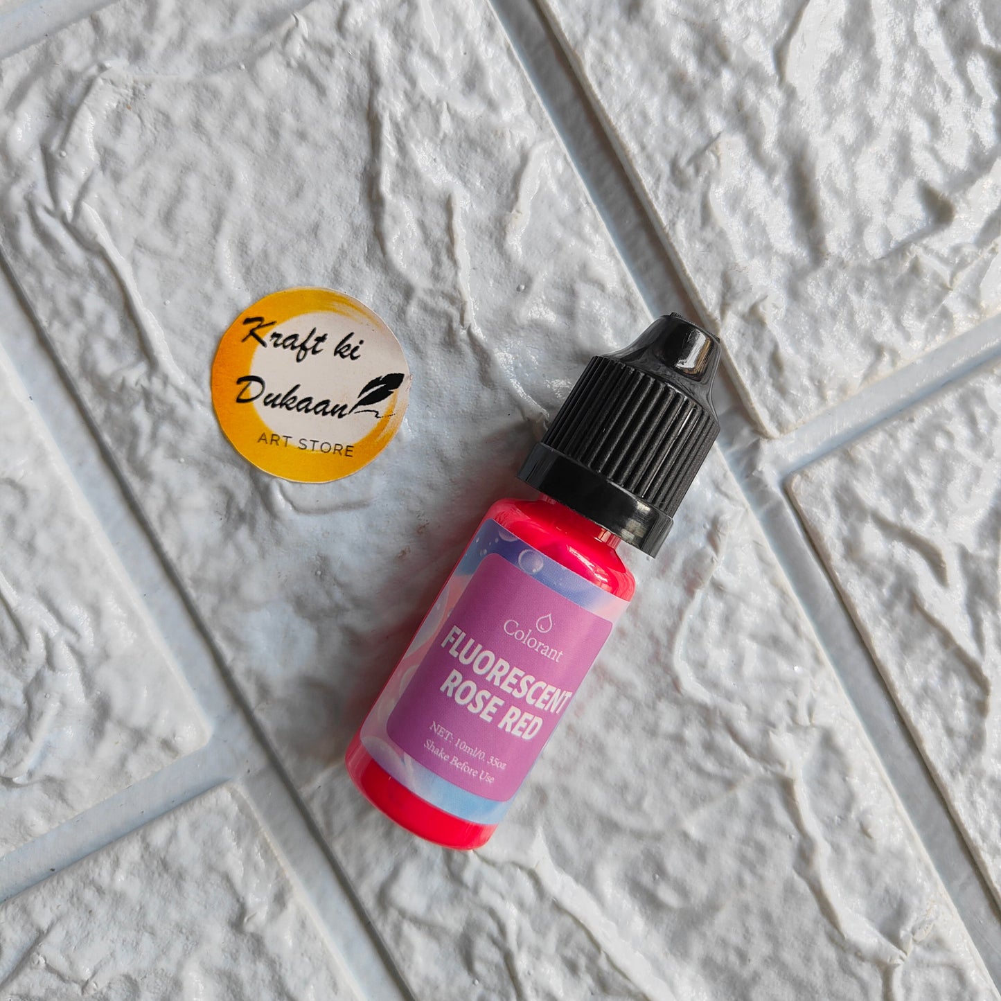 Fluorescent Rose Red resin pigment colorant bottle on textured surface for crafting projects