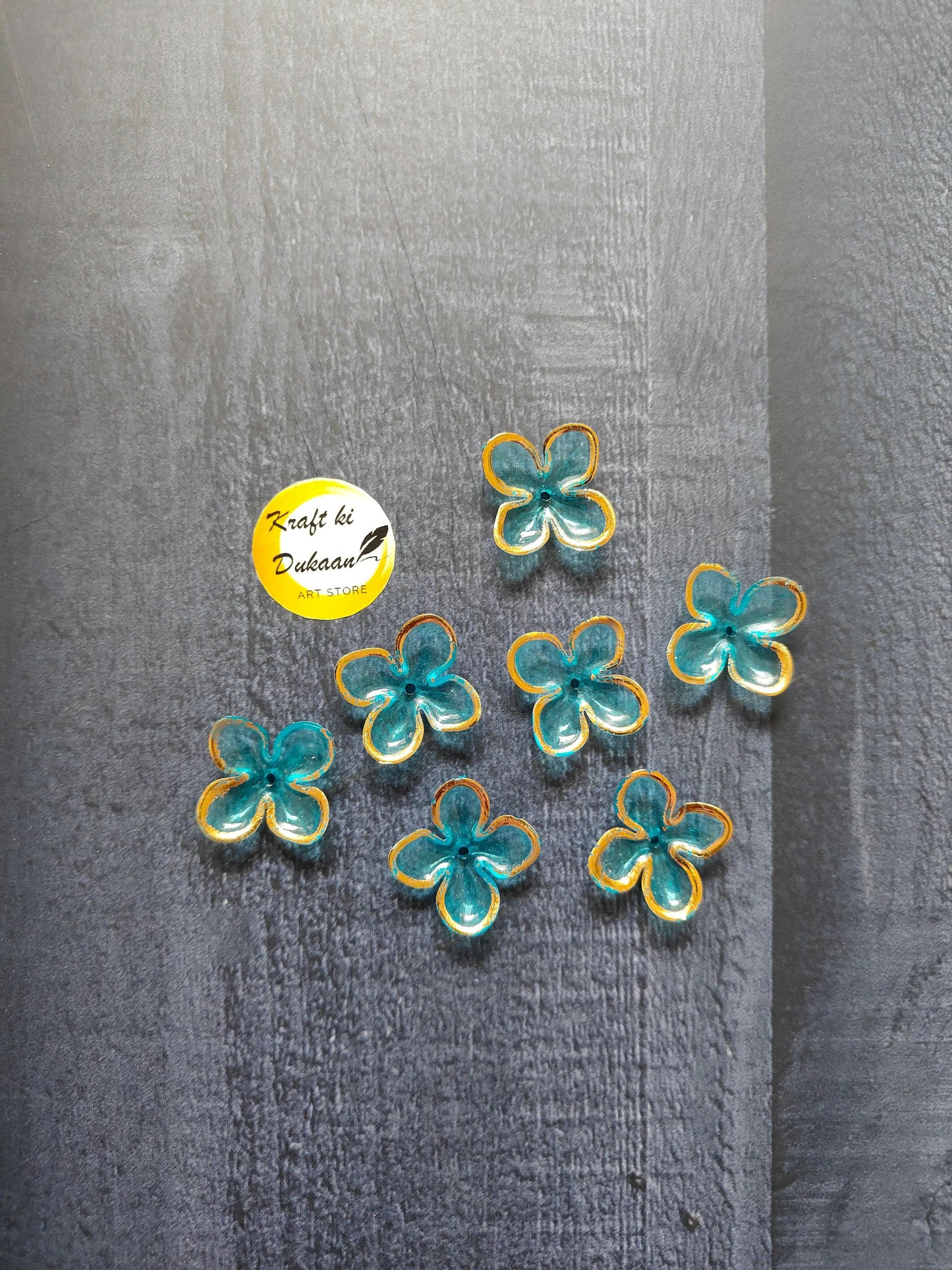 Turquoise flower beads with yellow edging, scattered on surface