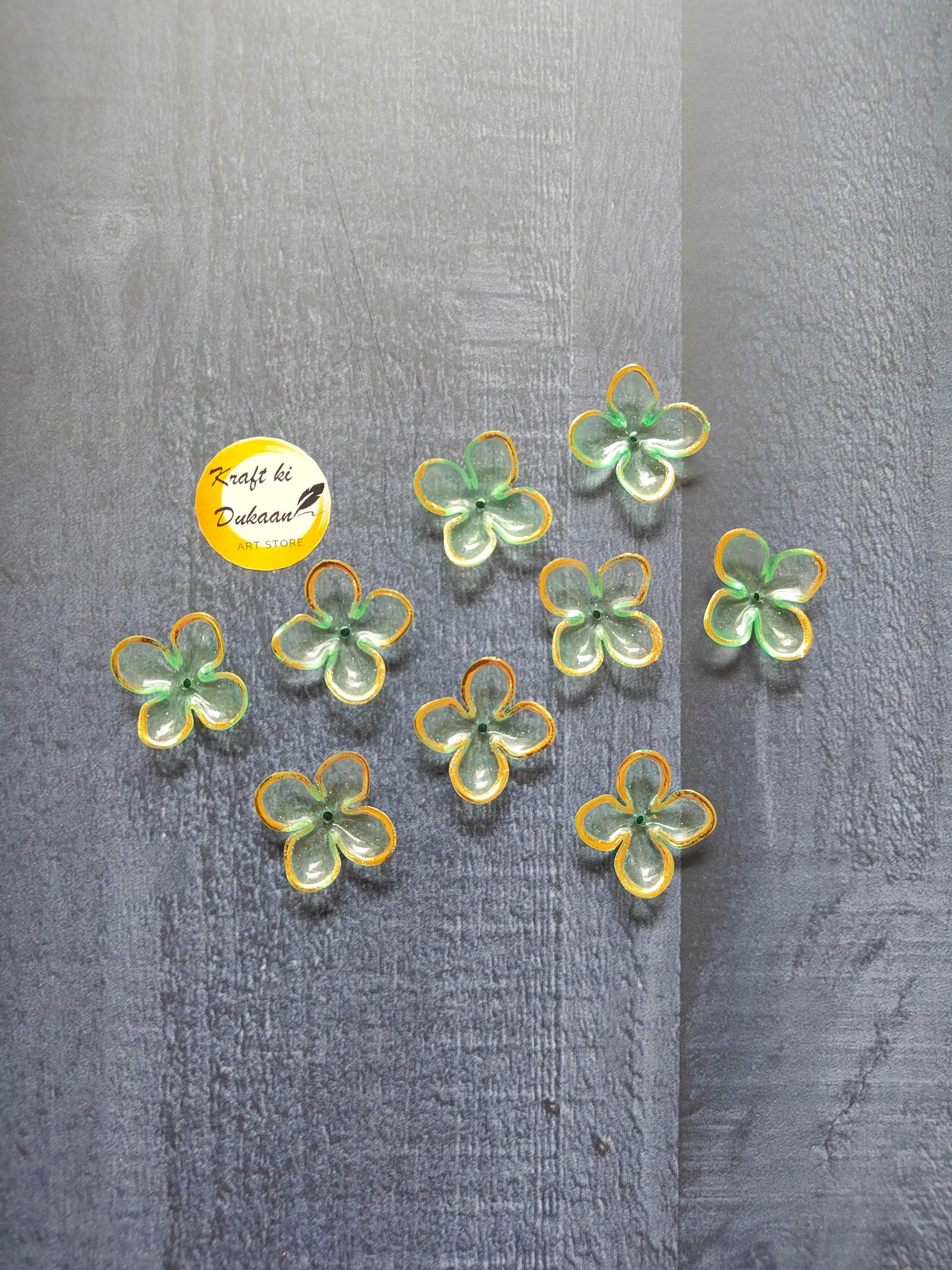 Flower-shaped bead charms in green, yellow, and blue with metal loops