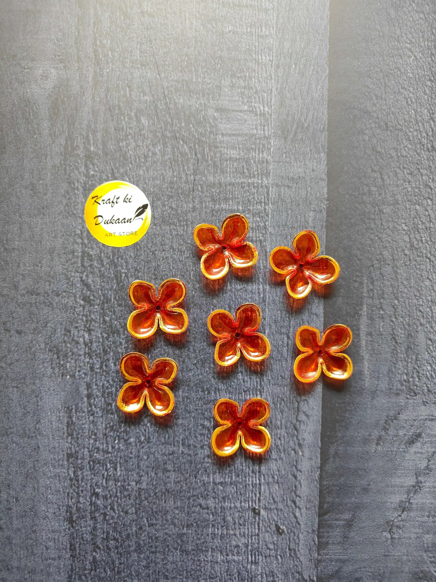 Orange flower beads with red edging, scattered on surface