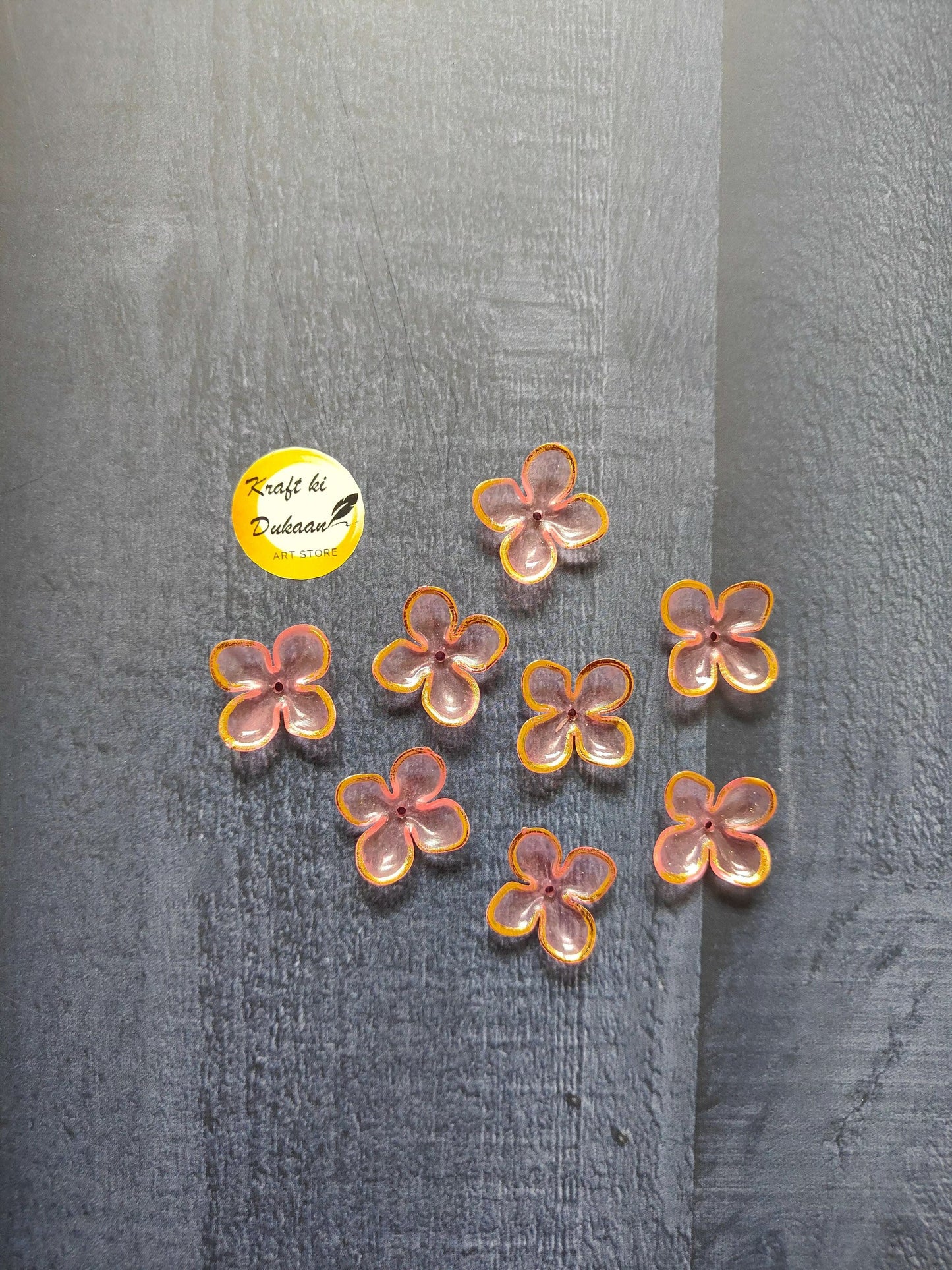 Pink flower beads with orange and yellow edging, scattered on surface