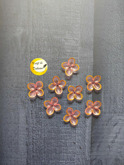 Pink flower beads with orange and yellow edging, scattered on surface