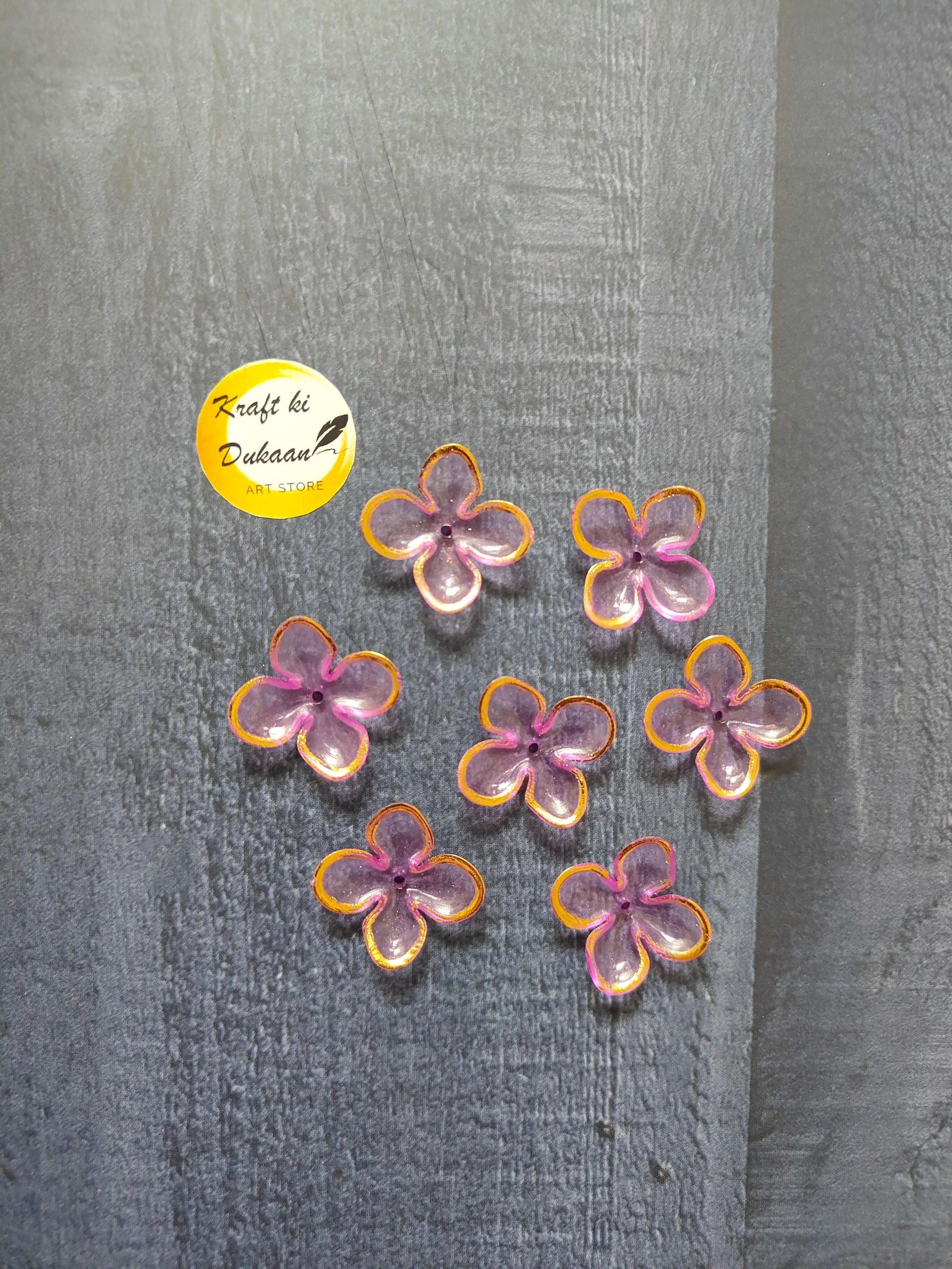 Pink and purple flower beads with orange edging, multiple on surface