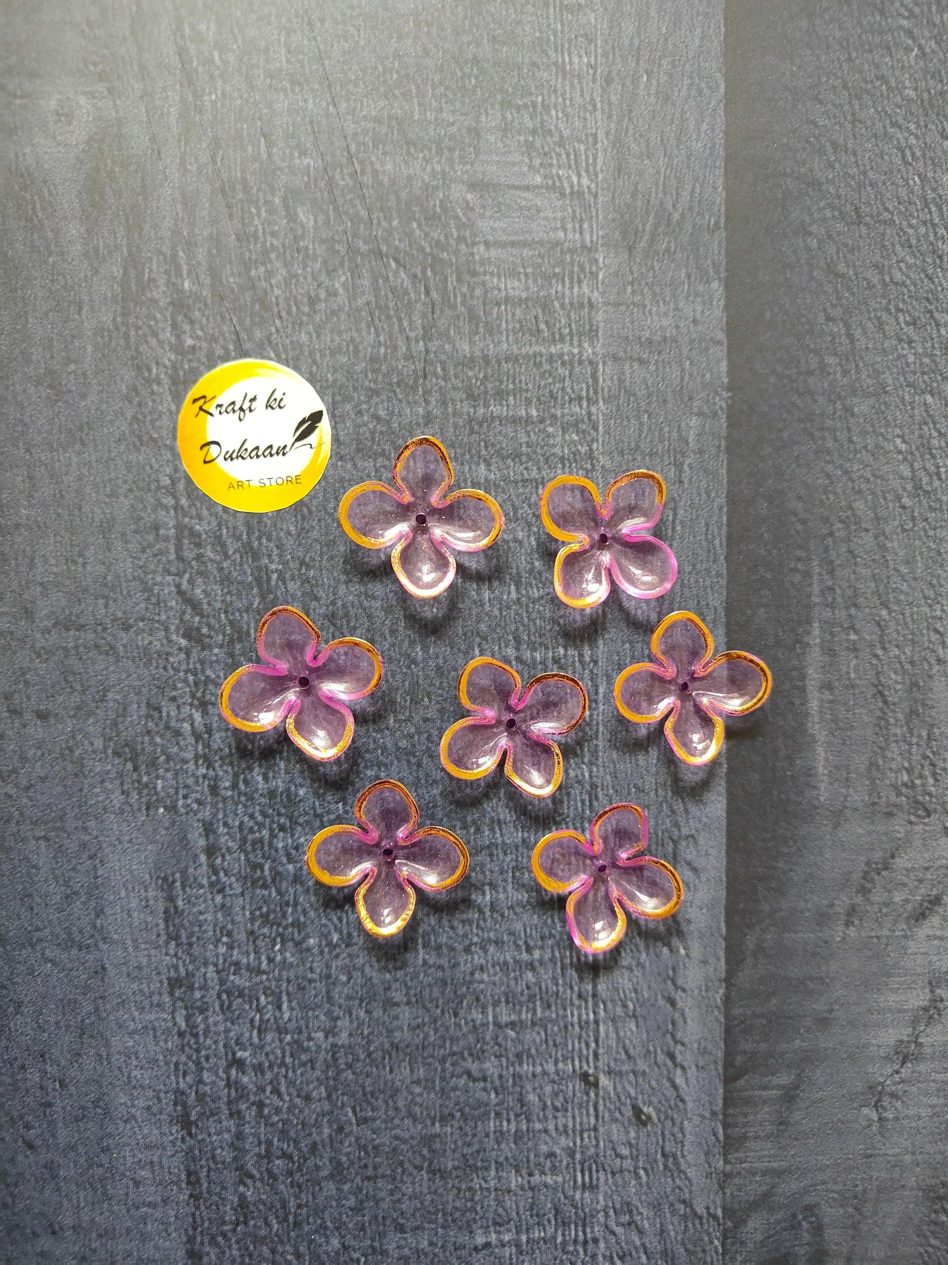 Pink and purple flower beads with orange edging, scattered on surface