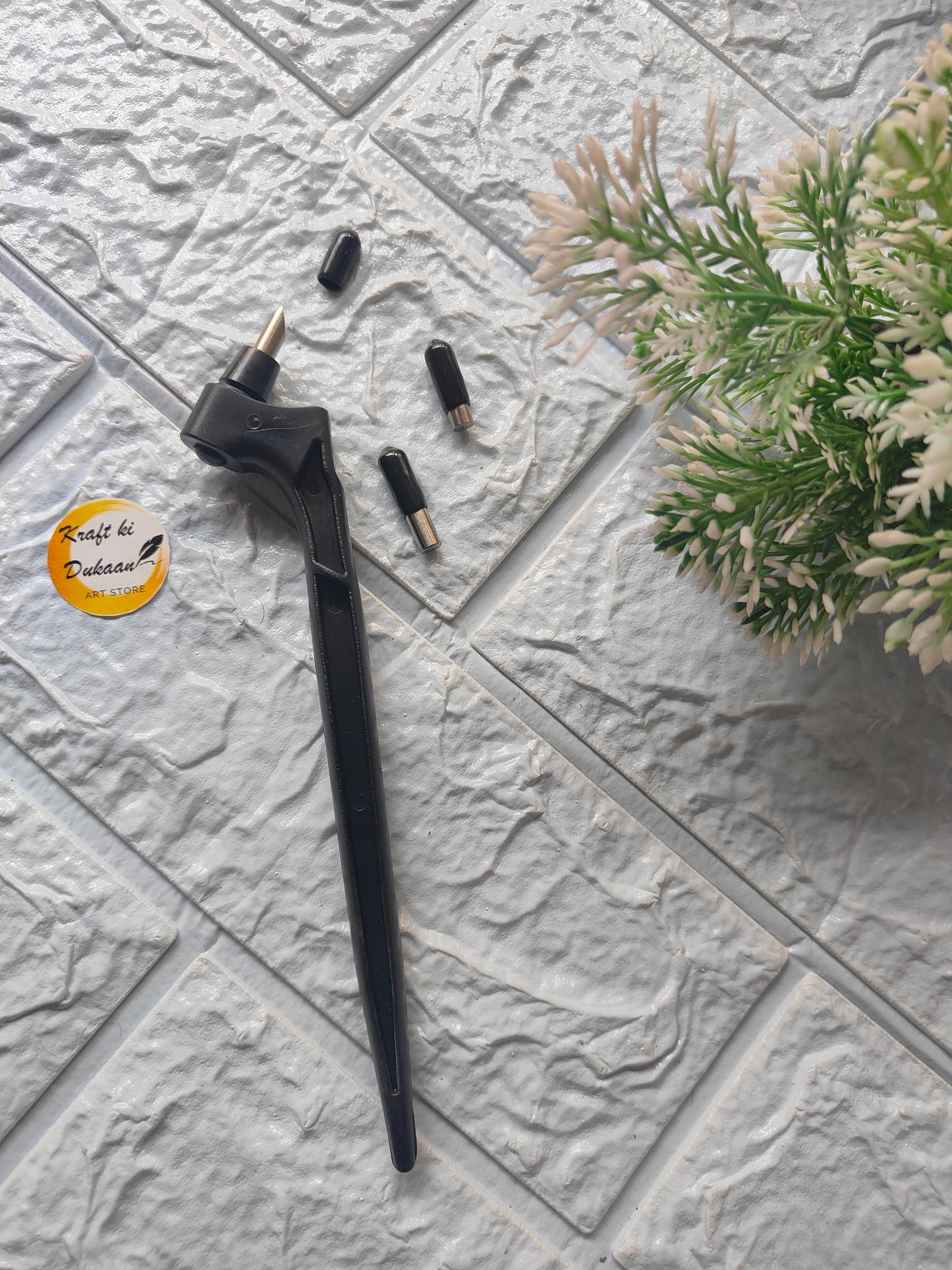 Black 360-degree rotating cutting tool with interchangeable tips on textured gray surface near green plant