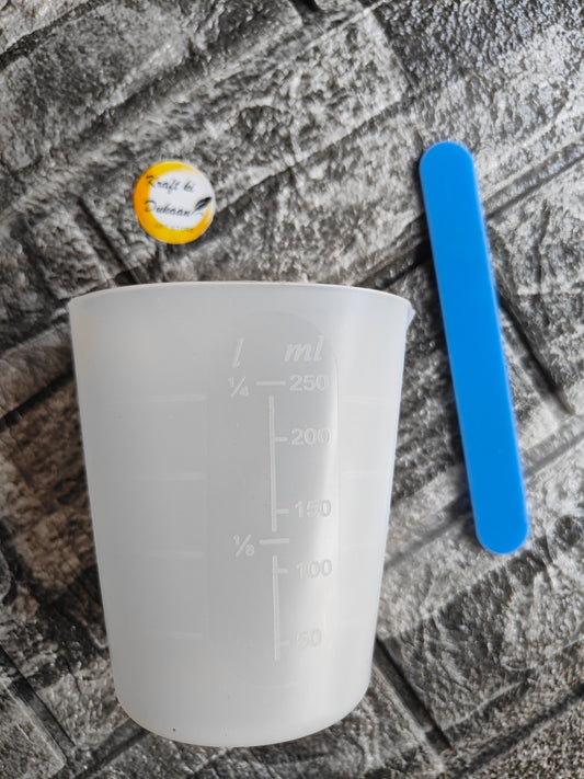 Clear silicone measuring cup for resin with blue mixing stick and Kraft ki Dukaan label on textured surface