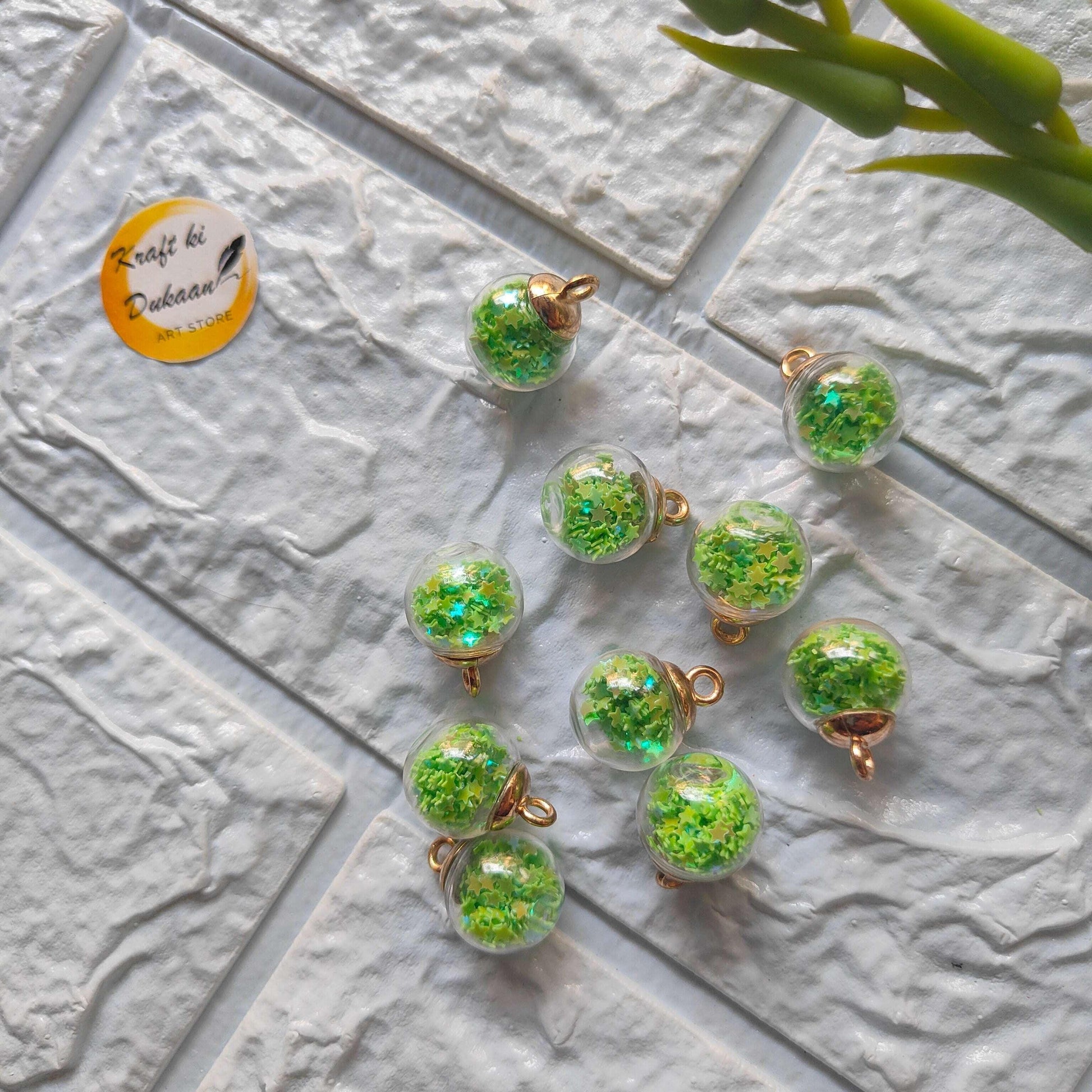 Glass ball pendants set, green glitter-filled spheres with gold caps and hanging loops