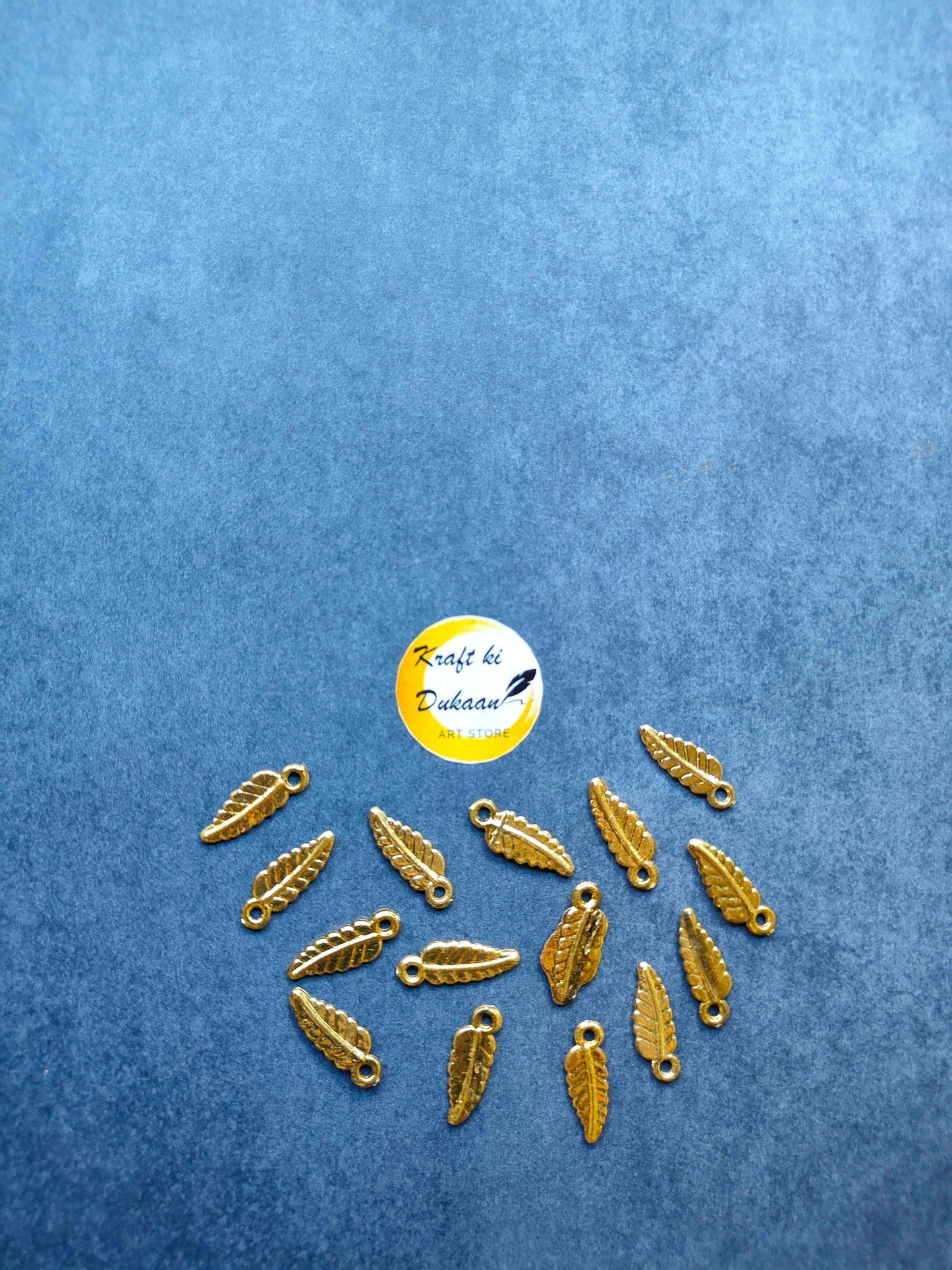 Gold-toned leaf-shaped plastic charms with loop, pack of 100