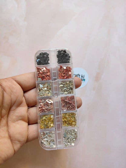 Handheld clear case with compartments of black, rose, gold, and silver stone crystal chips