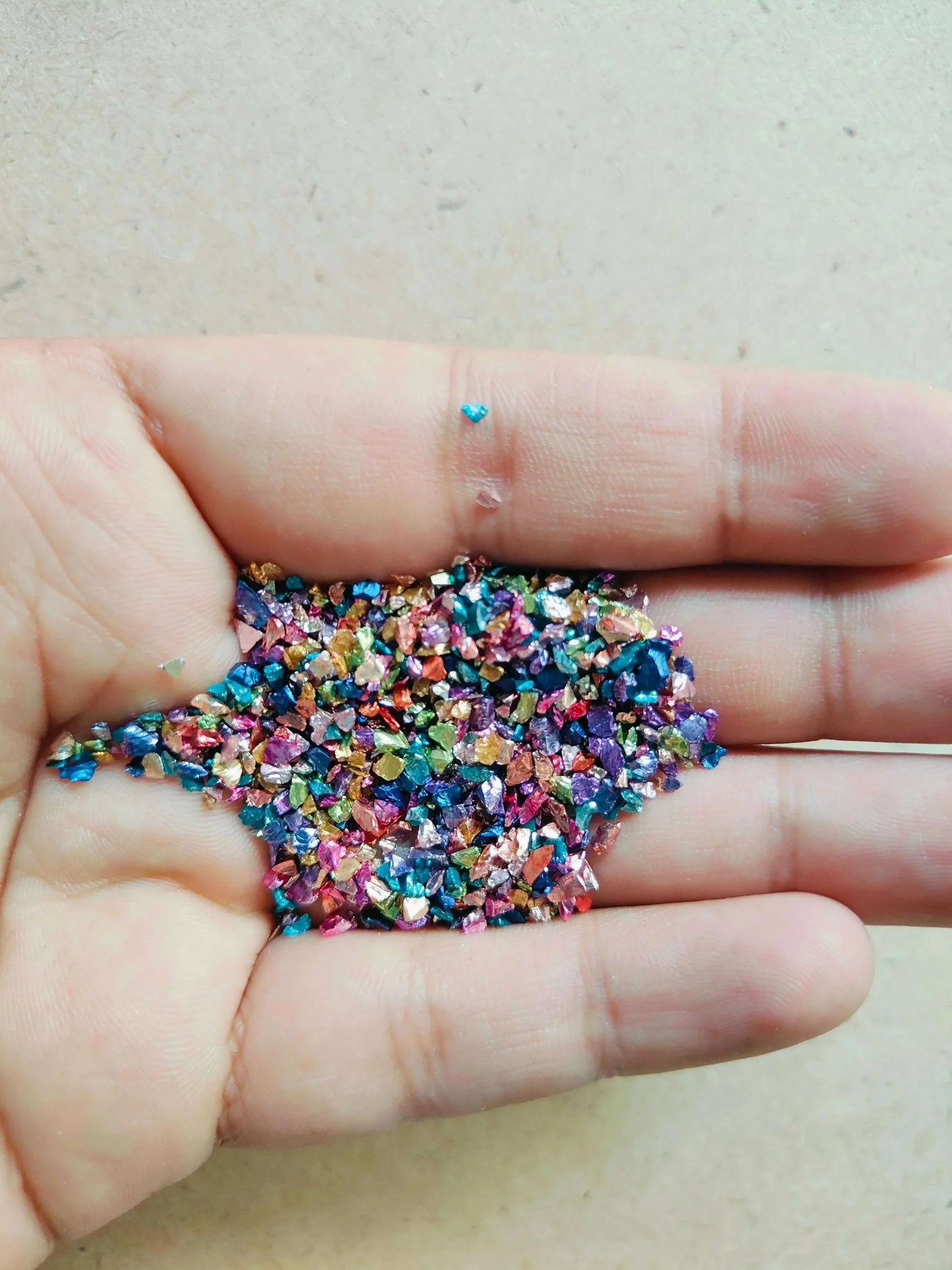 Hand holding multicolor granule stones for resin art, showcasing vibrant colors and textures