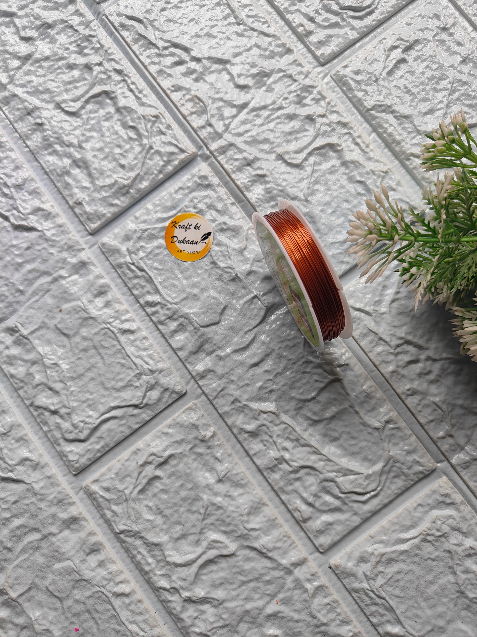 Craft wire roll 0.4mm in copper color placed on textured background for various crafting projects