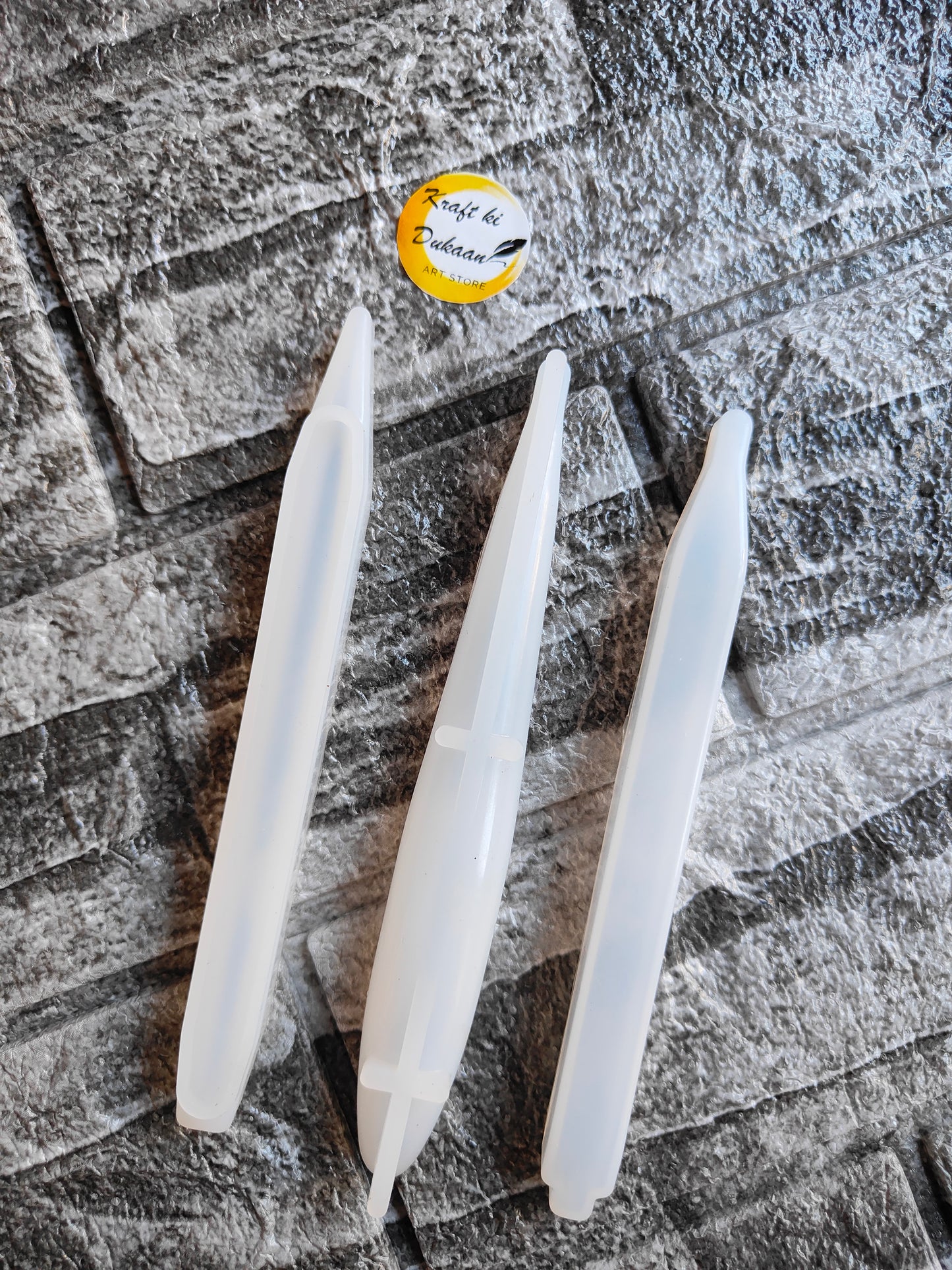 Clear resin pen mold set by Kraft ki Dukaan with three pen-shaped silicone molds on textured surface