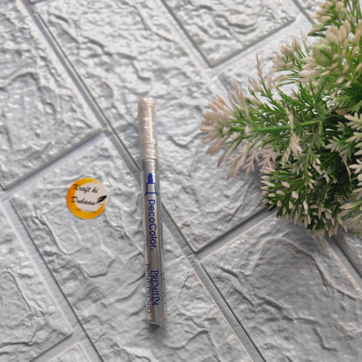 Kraft ki Dukaan thin tip deco marker on textured surface with decorative plant nearby