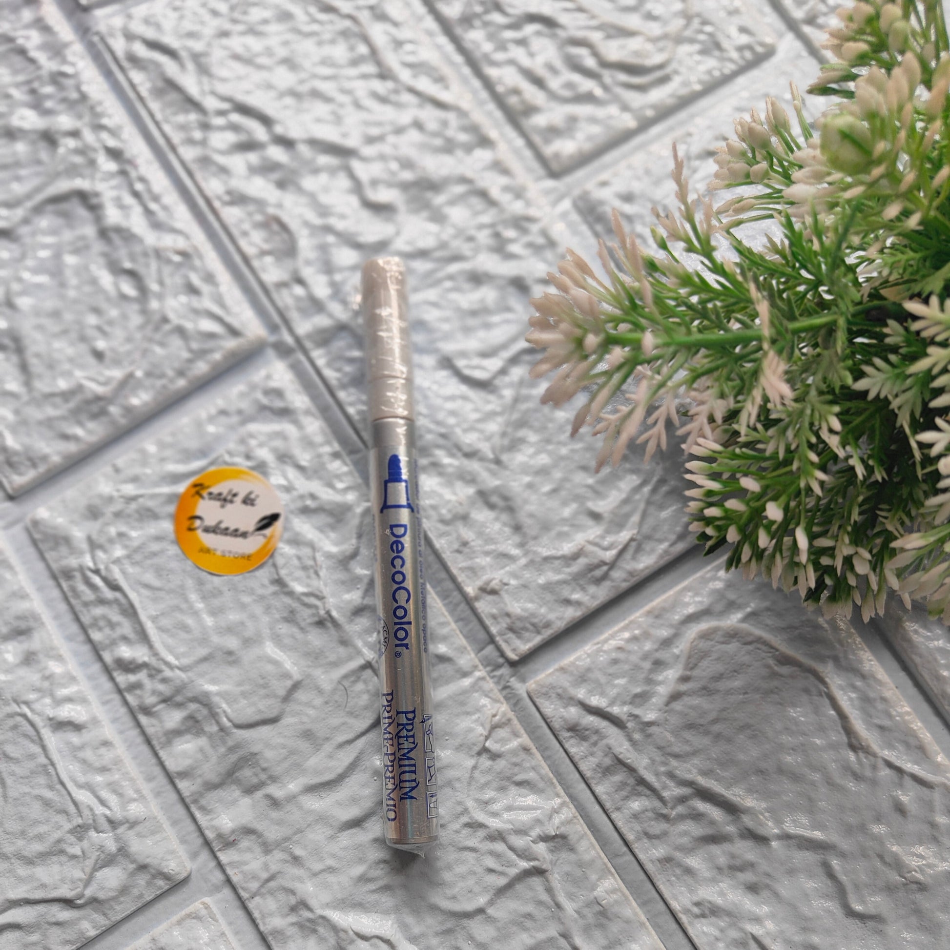 Kraft ki Dukaan thin tip deco marker on textured surface with decorative plant nearby