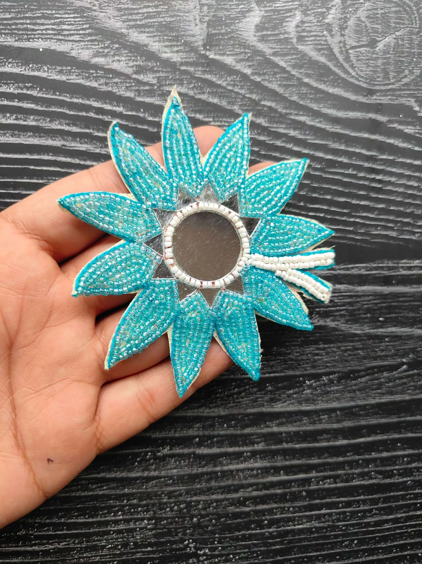 Beaded flower patch with teal blue petals and round gray center.