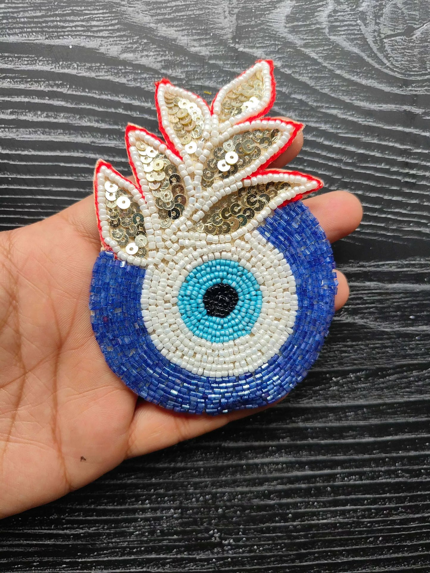 Decorative eye bead patch with gold sequin wings, blue base, turquoise center eye