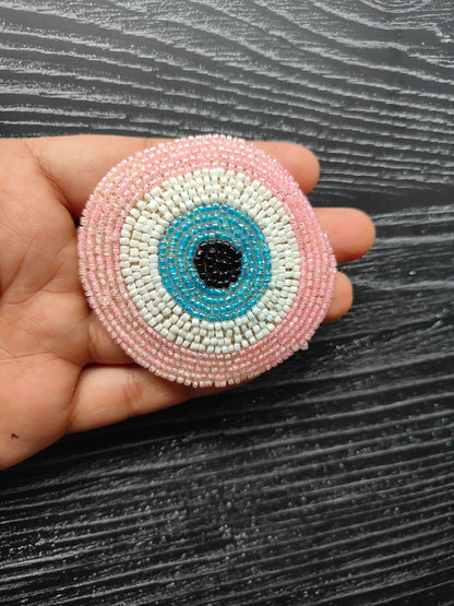 Baby pink circular beaded eye patch with blue center ring and white outer border