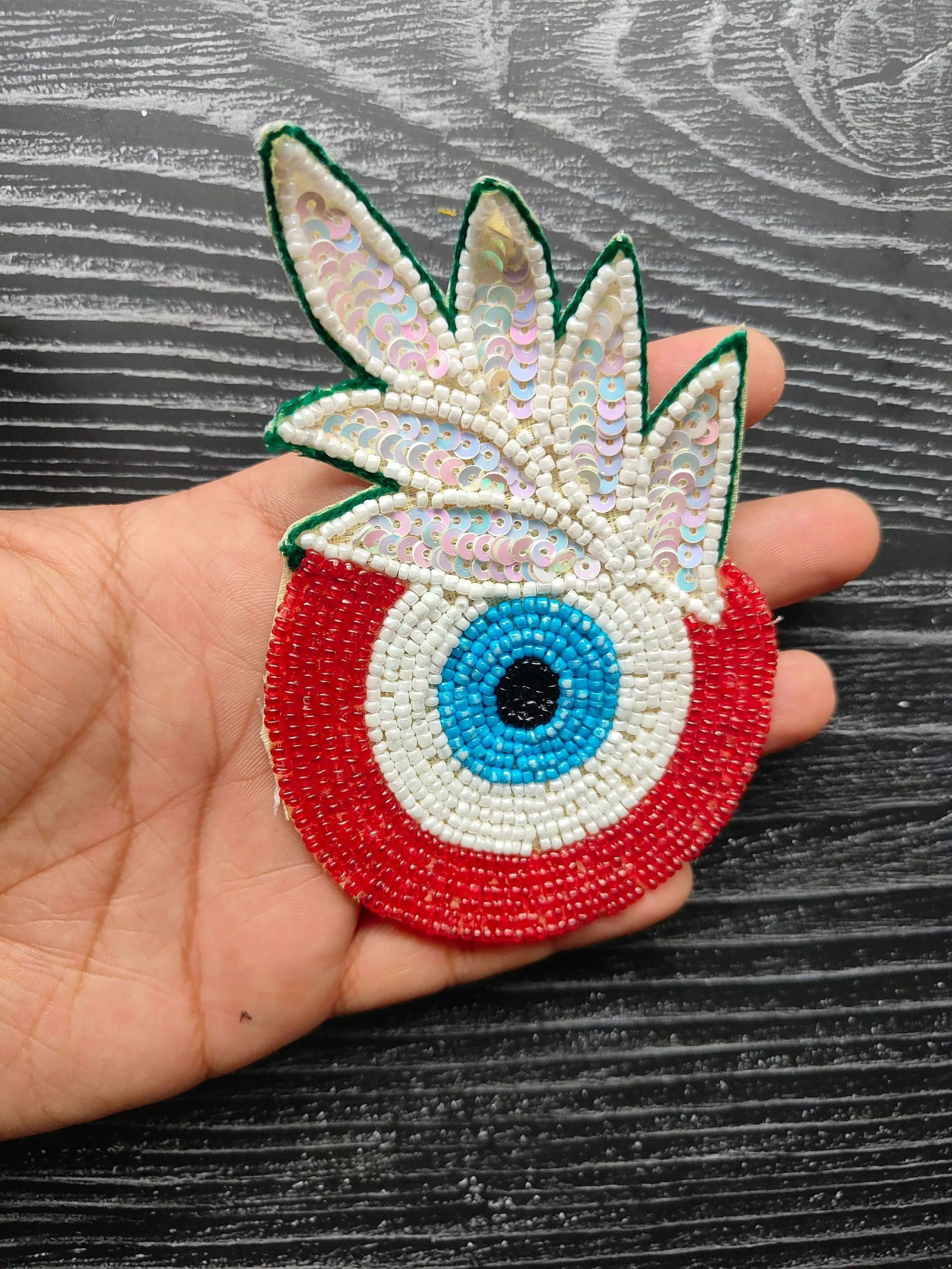 Decorative eye bead patch with green sequined wings and red circular base