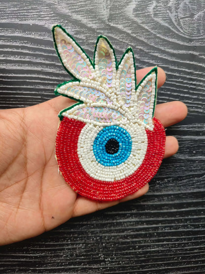 Decorative eye bead patch with green wings, red base, blue center eye