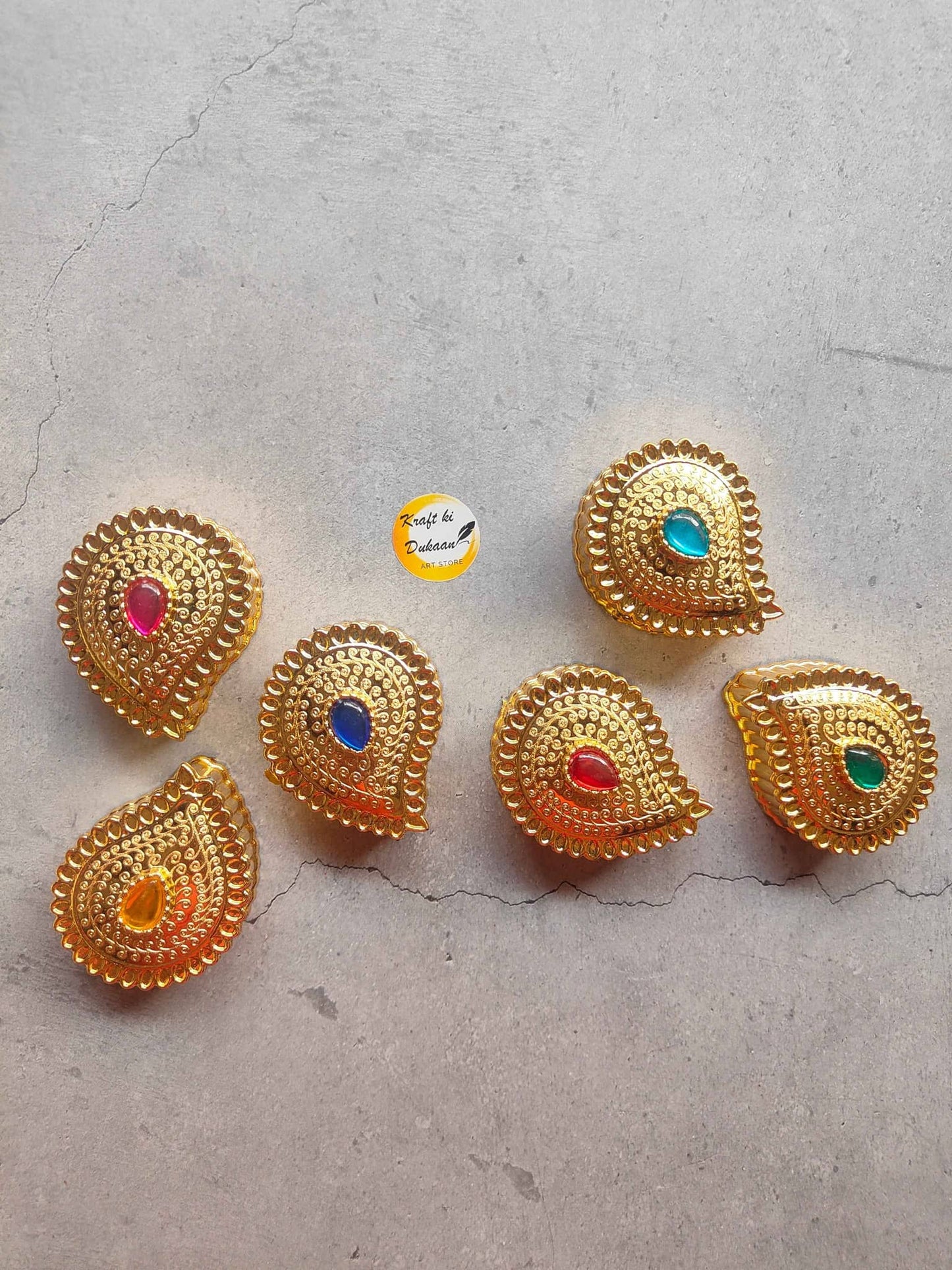 Set of six golden decorative roli chawal boxes with colorful gems for festive celebrations