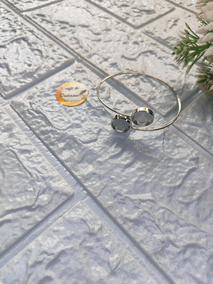 Gold-tone bracelet with two round dark discs on a thin open bangle