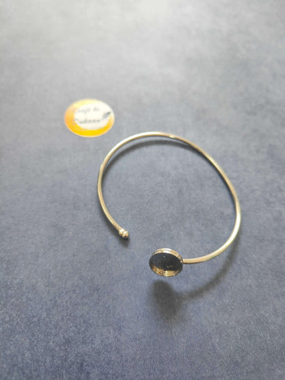 Gold-tone bangle bracelet with small bead clasp and round medallion