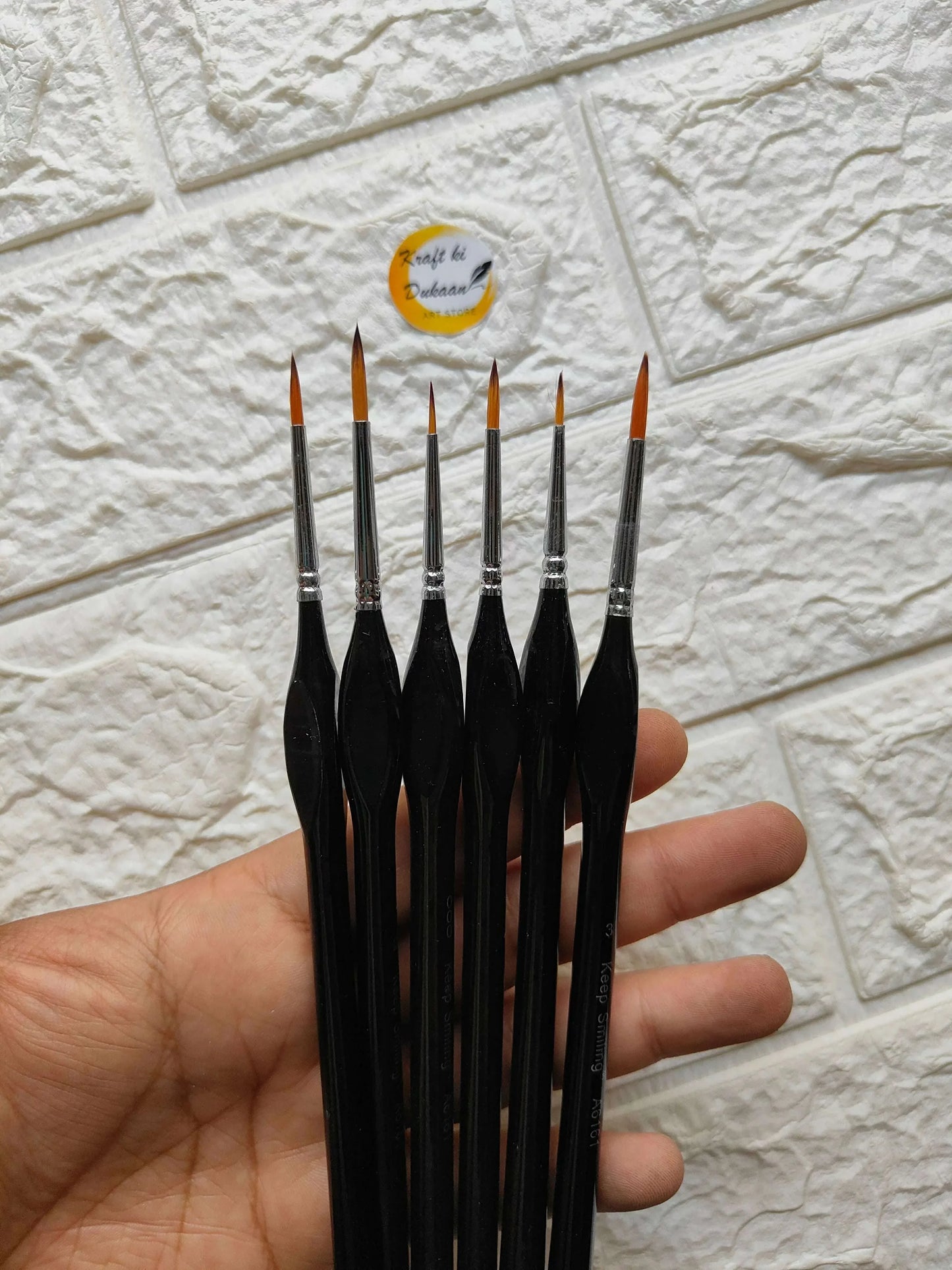 6pc detail liner brush set held in hand; slim black brushes with orange tips