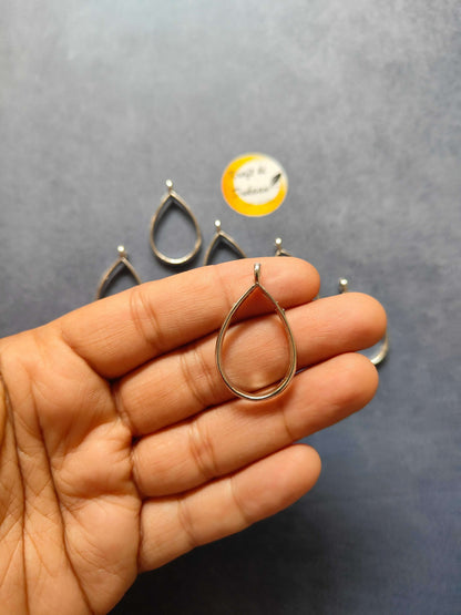 Silver teardrop drop bezel pendant charm held in hand, part of 10pc set