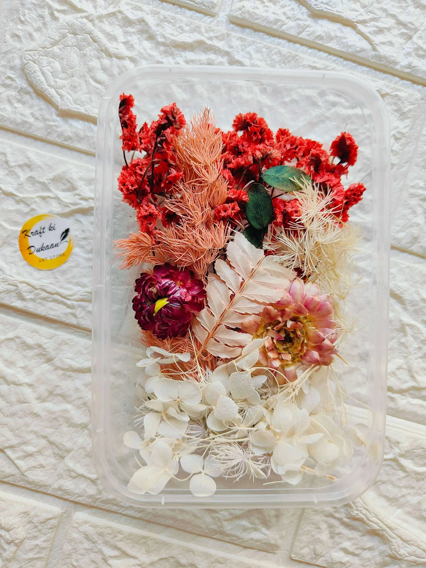 Dry flower box with red, peach and white dried blooms in clear plastic case