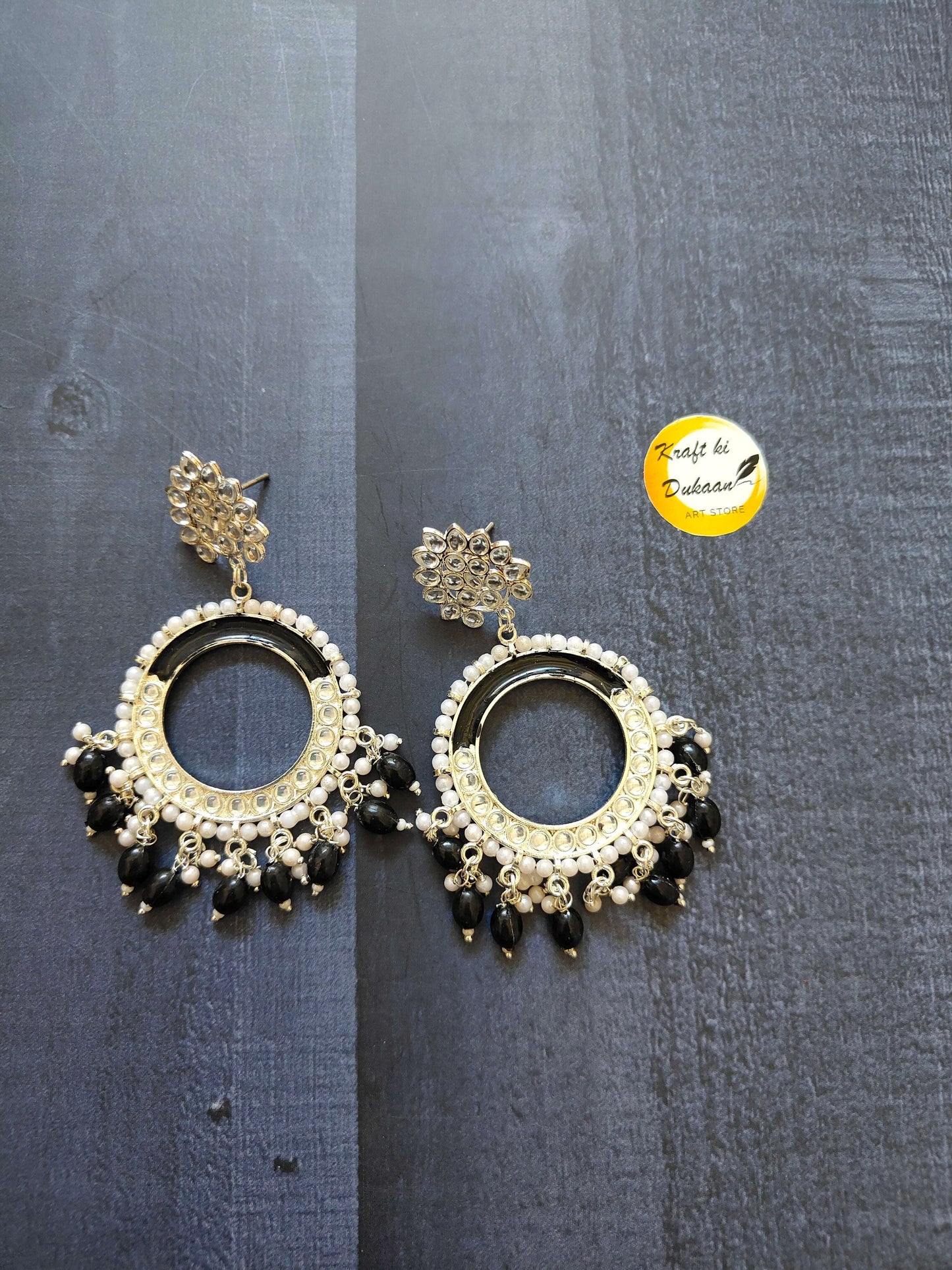 Gold-tone chand bali earrings with dark center hoop, white beads, and tassel fringe.