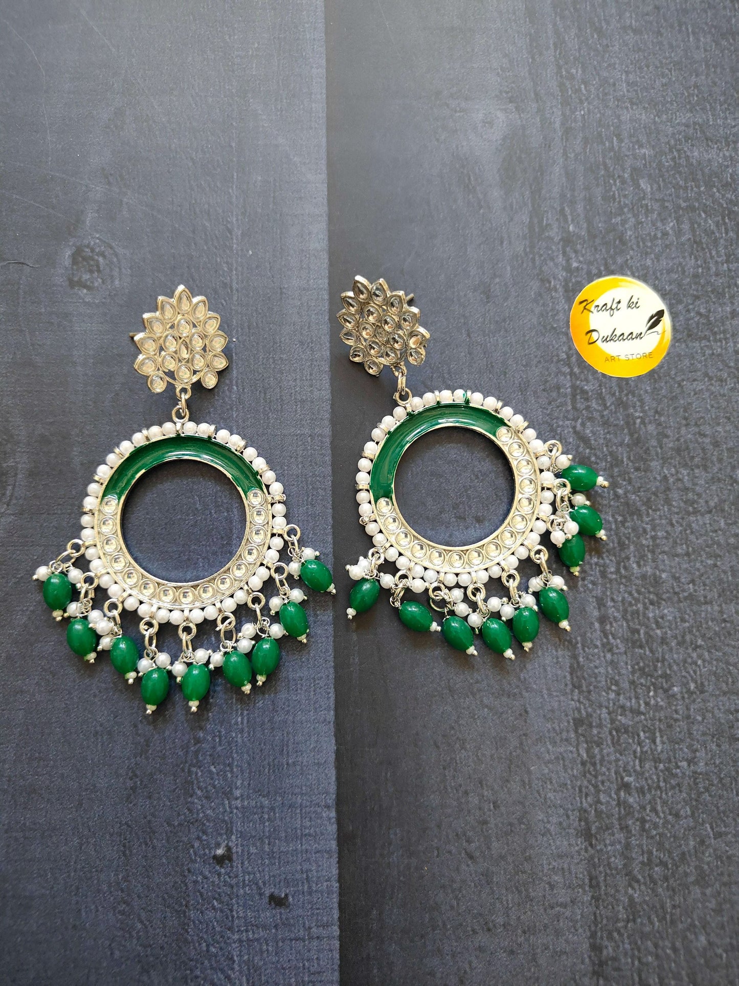 Gold-tone chand bali earrings with green stone rim and dangling green beads.