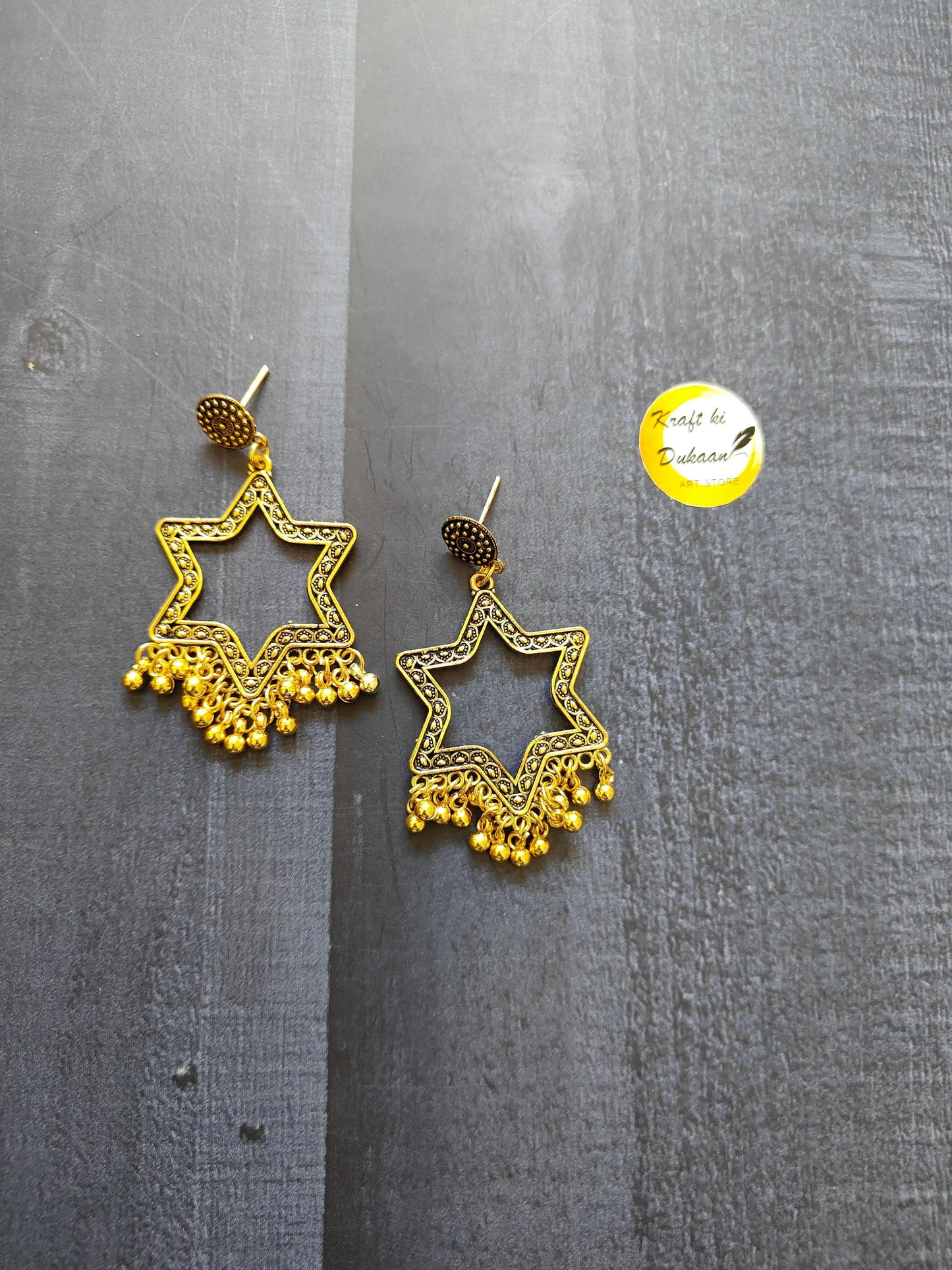 Golden jhumka star dangle earrings with textured round cap and gold-tone fringe, no beads