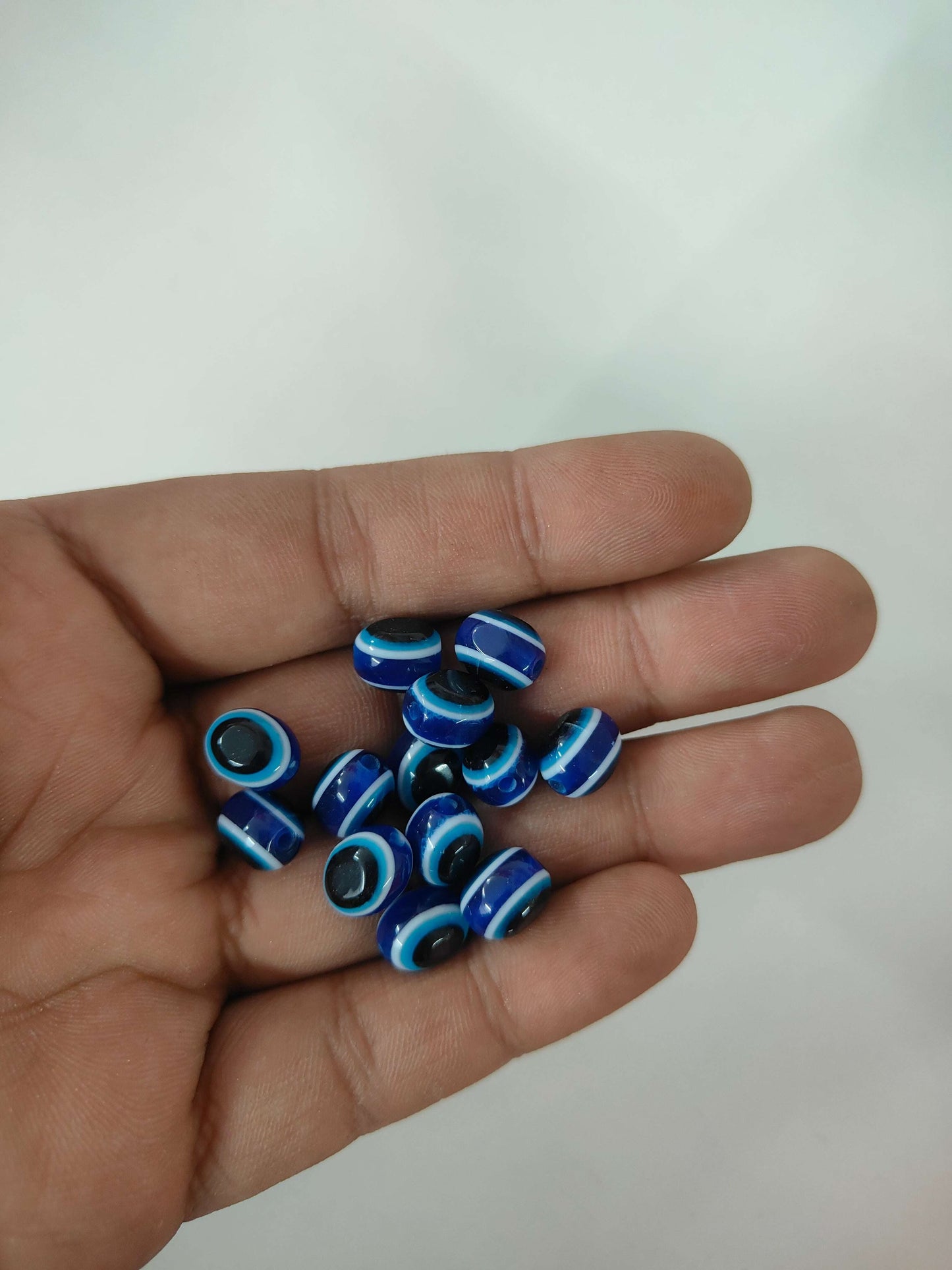 Blue oval evil eye beads with black center rings, 25-pack in hand
