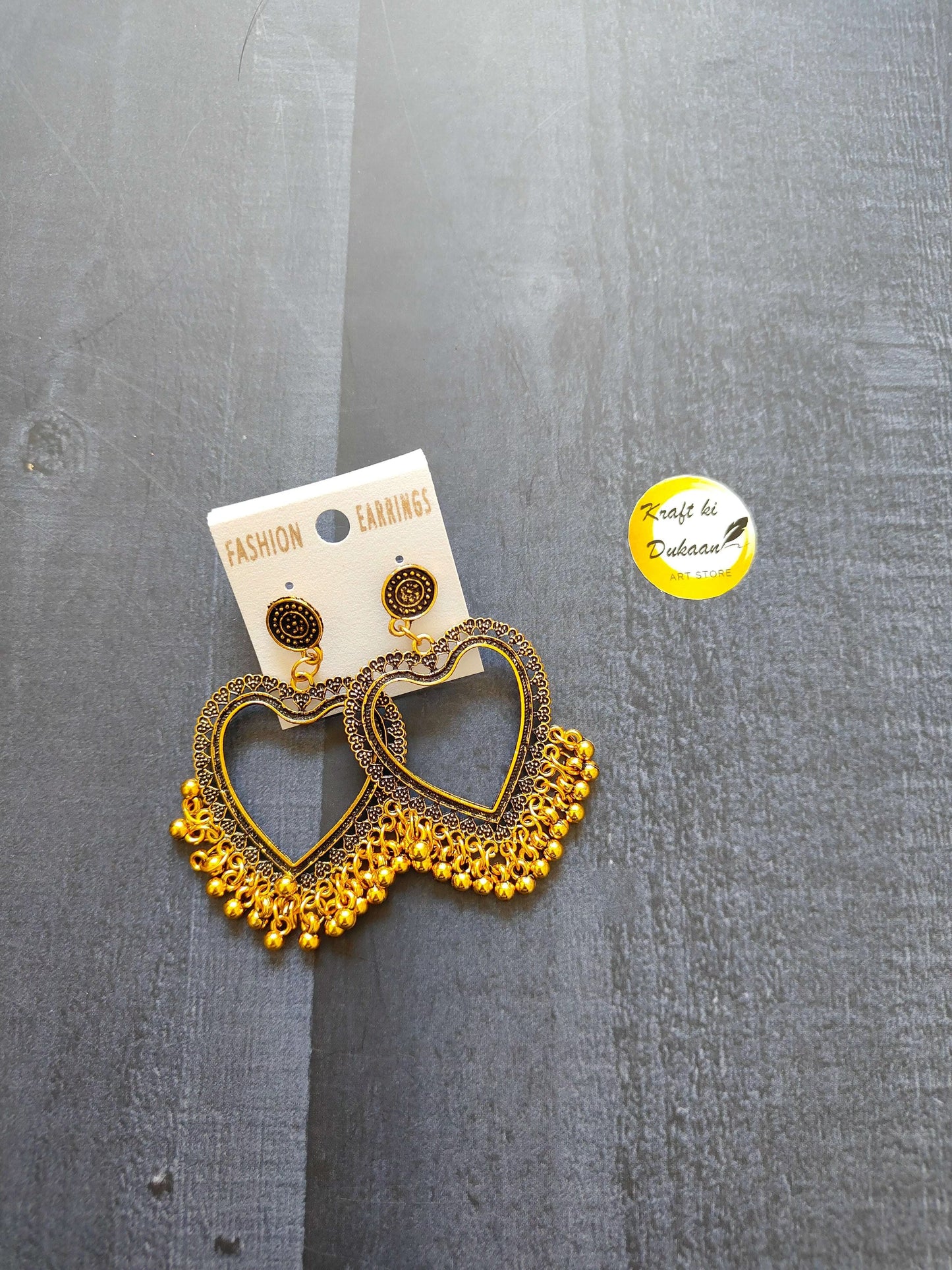 Golden jhumka-style earrings with heart motifs, intricate gold-tone detailing, no beads