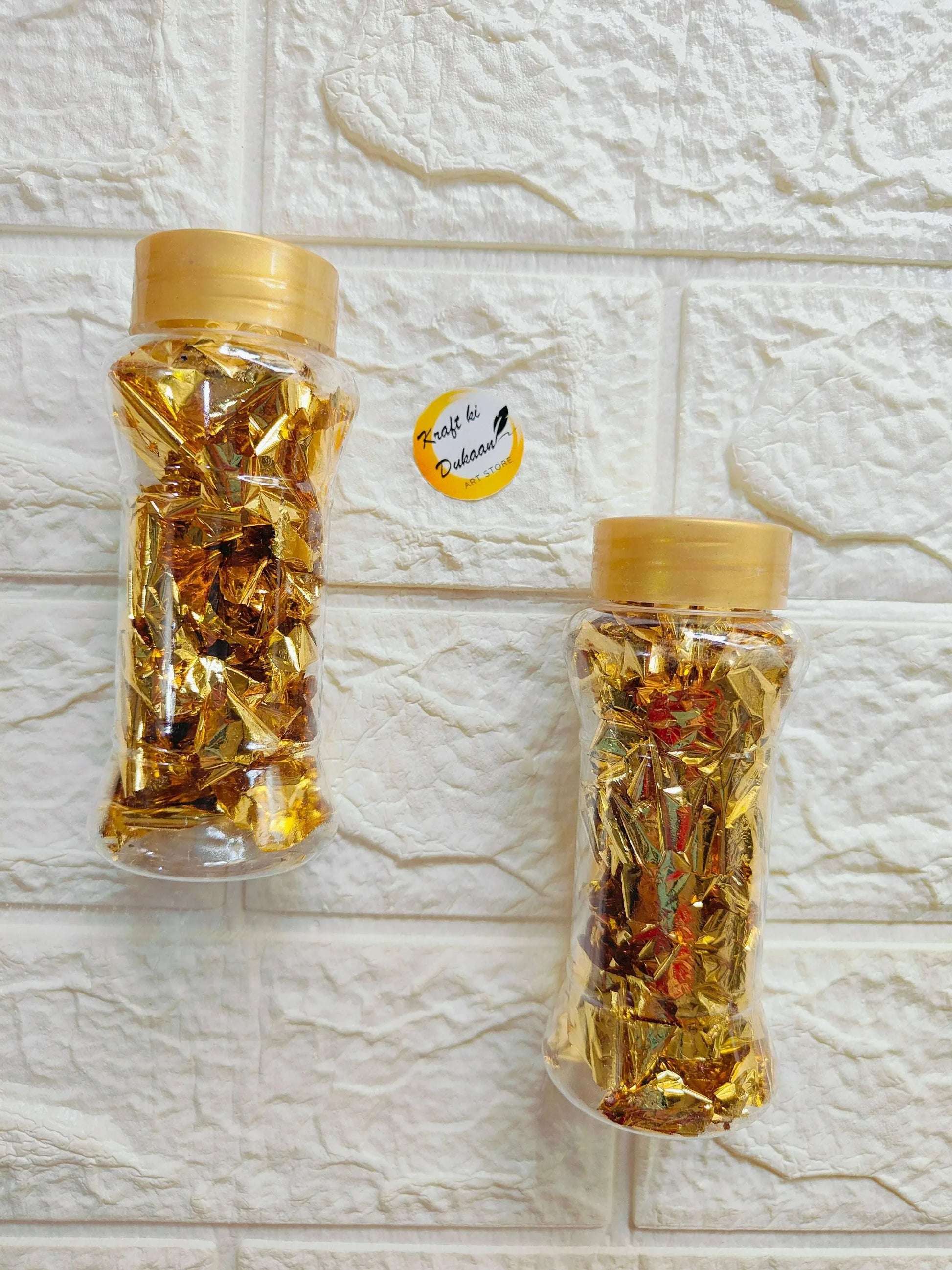 Gold foil flakes in jars with gold caps, shiny metallic flake pieces