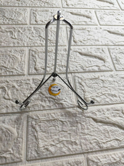 Silver folding metal stand with top handle loop and three support feet