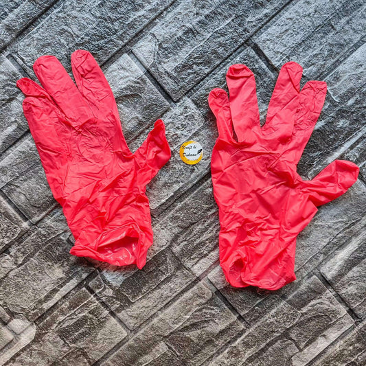 Pair of red vinyl hand gloves, laid flat with finger openings visible