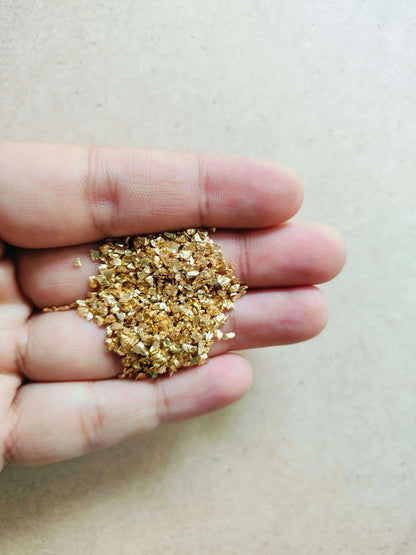 Hand holding shimmering gold stones for resin art suitable for crafting and decoration