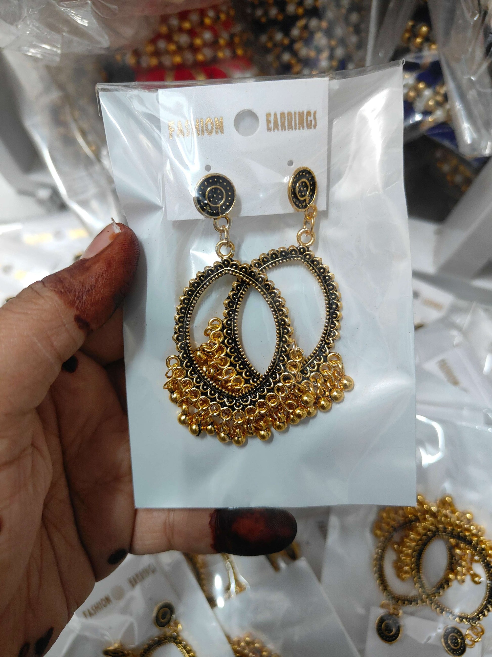 Gold-tone eye-shaped jhumka earrings with ornate oval cutout and dangling drop charm