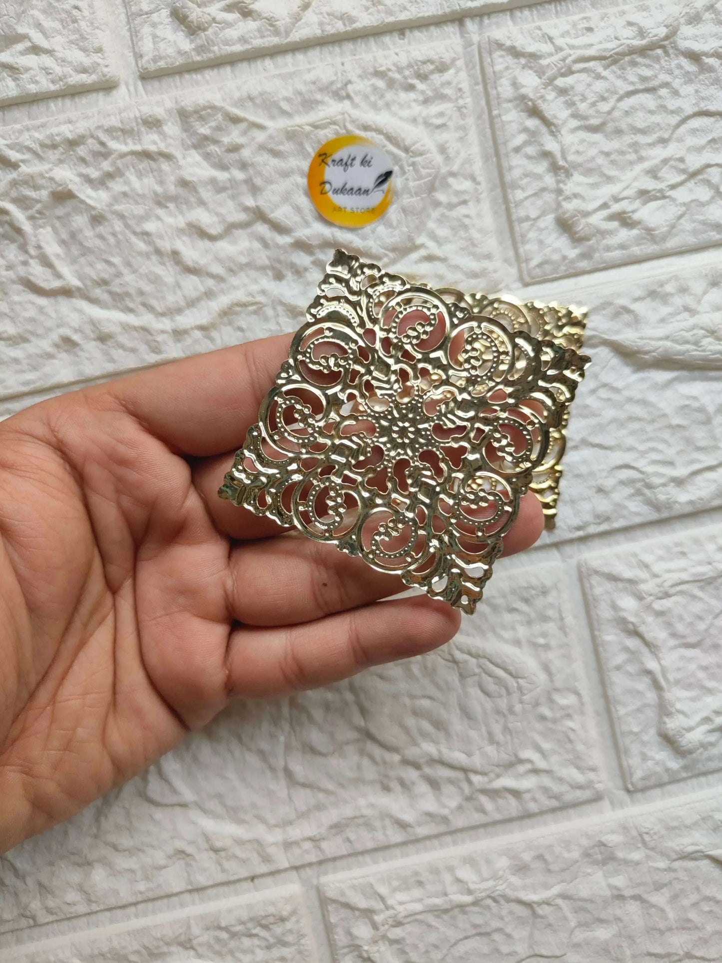 Golden square tea light plate in ornate filigree design held in hand