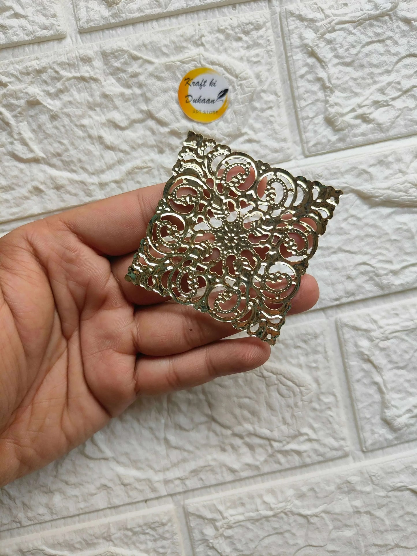 Hand-held view of golden square t-light plate with ornate openwork filigree