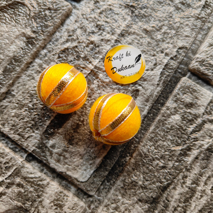 Two vibrant yellow Gota Patti craft balls with decorative golden embellishments