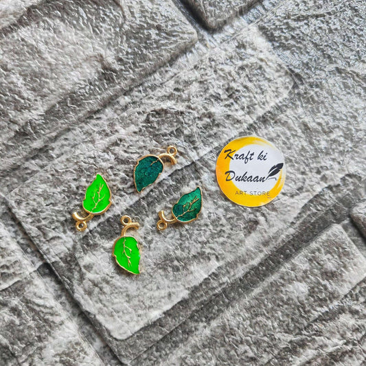 Green leaf metal charms set, gold-tone loops with enamel leaves in flat lay