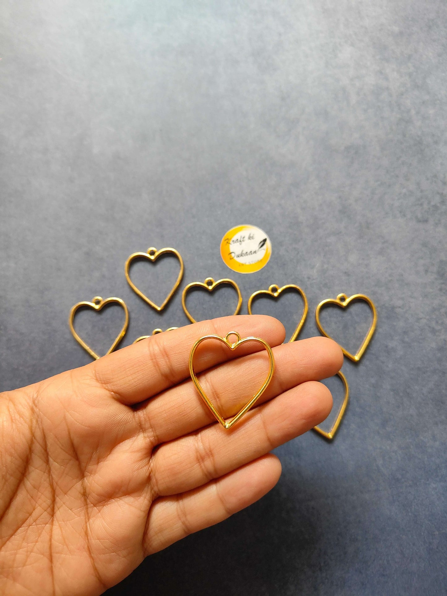 Gold heart bezel pendant from the 10PC set, heart charm held in hand
