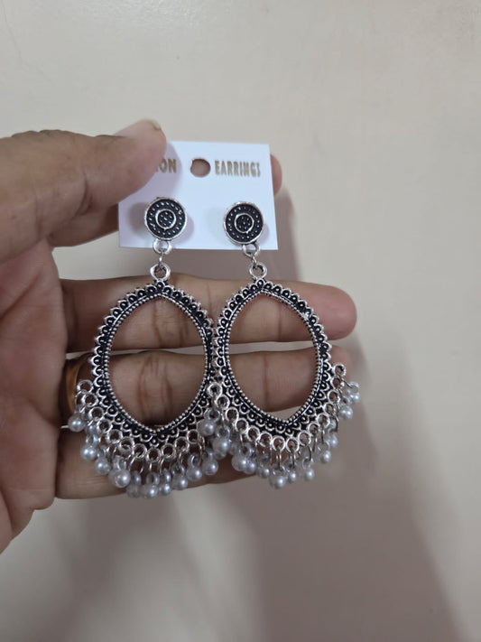 Elegant jhumka in silver with intricate design and dangling pearls, perfect for special occasions