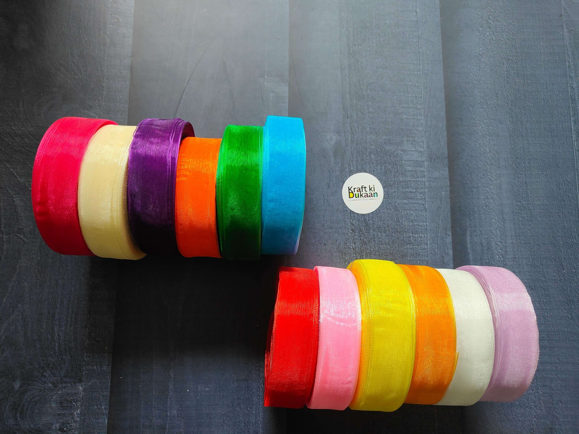 Assorted organza ribbon spools with red, purple, green, blue, yellow, pink bands.