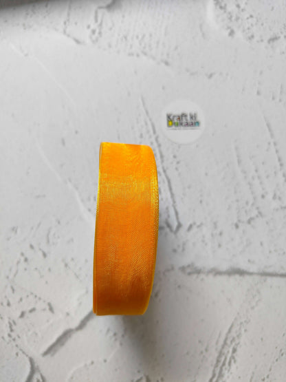 Orange organza ribbon roll, narrow sheer strip with woven texture.