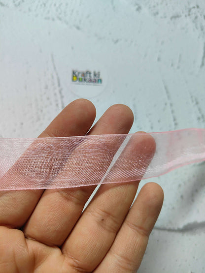 Pink organza ribbon strip held in hand, semi-sheer woven organza.