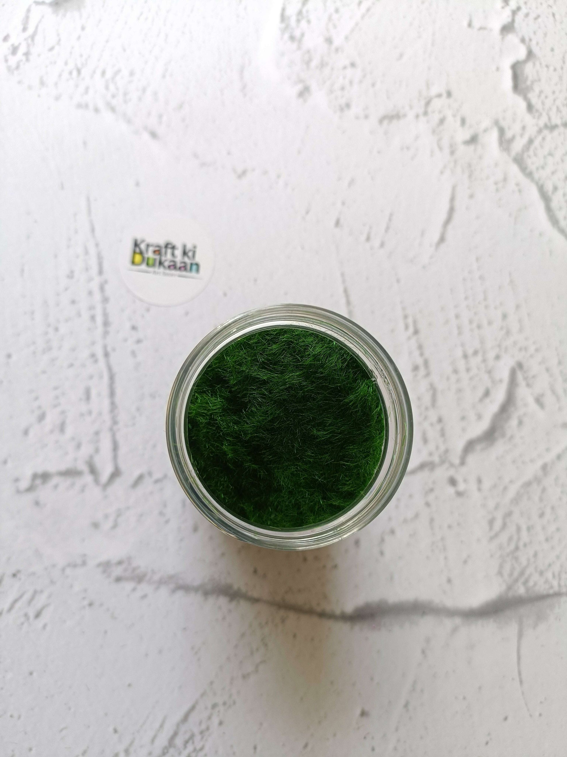 Artificial Grass 40GM dark green fibers in an open-top clear jar, viewed from above